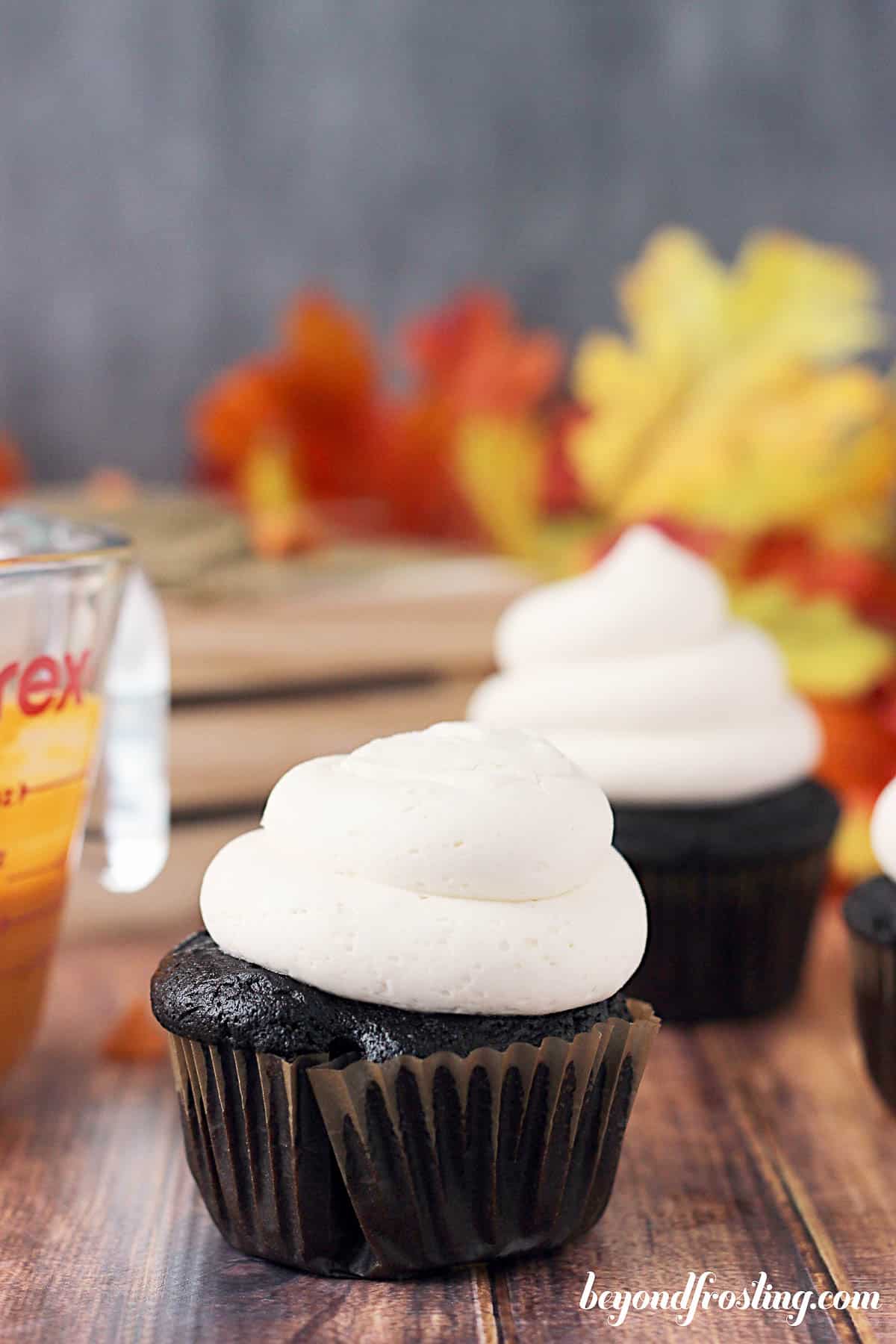 side view of a cupcake on a counter topped with frosting and another cupcake in the background