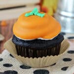closeup of a pumpkin spice chocolate cupcake decorated to look like a pumpkin