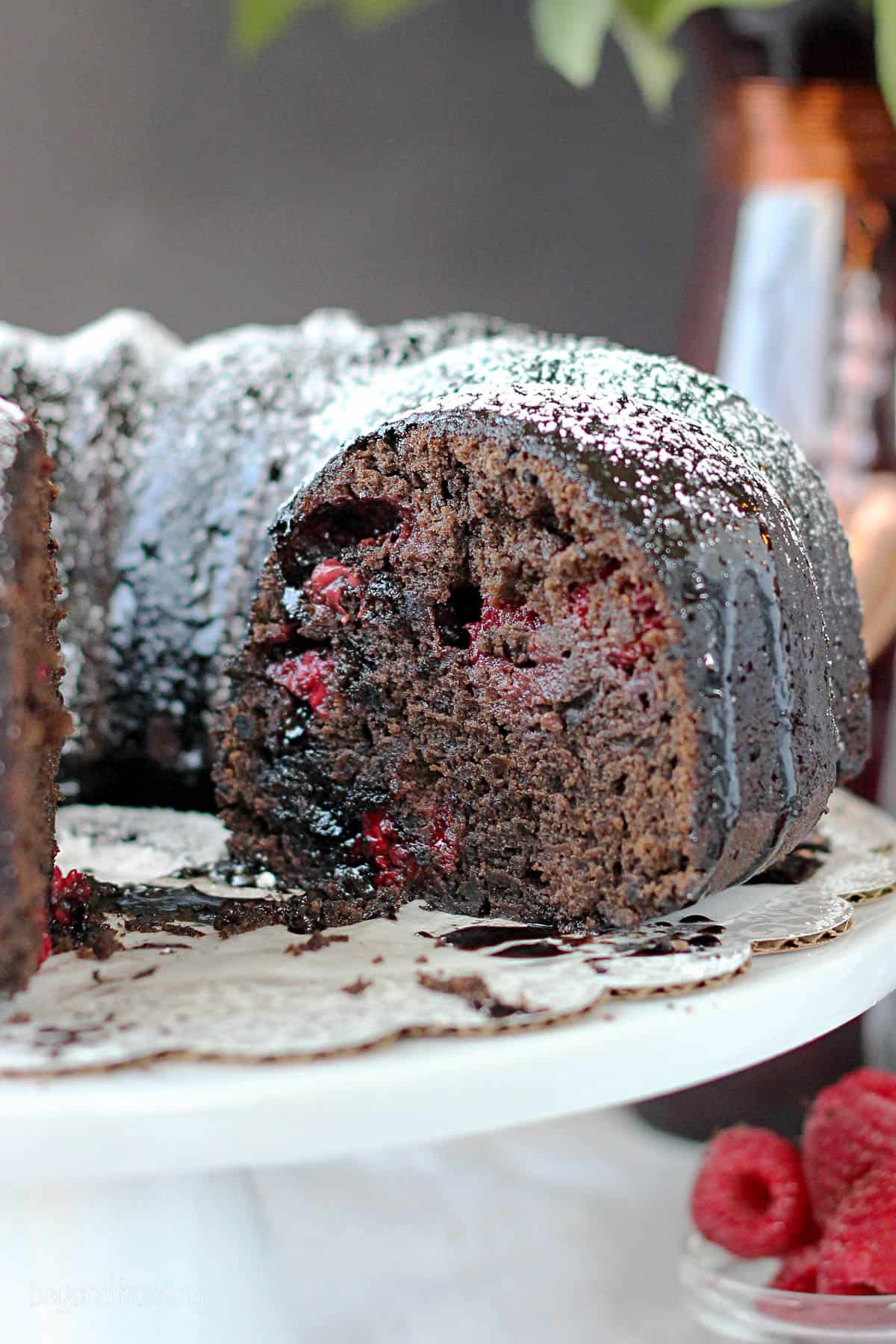 side view of a raspberry cabernet cake with a slice cut out on a cake stand