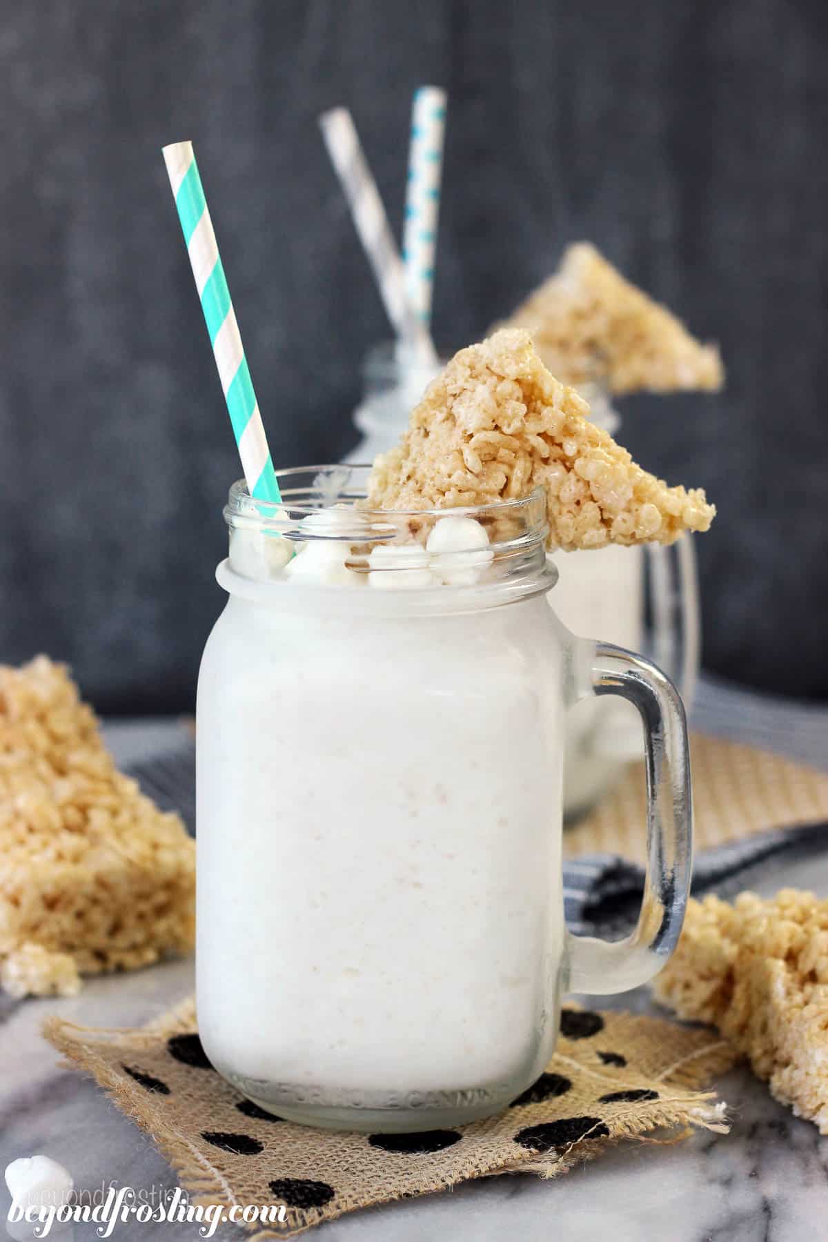 side view of a jar full of a rice krispie treat milkshake garnished with marshmallows and a triangle rice krispie treat