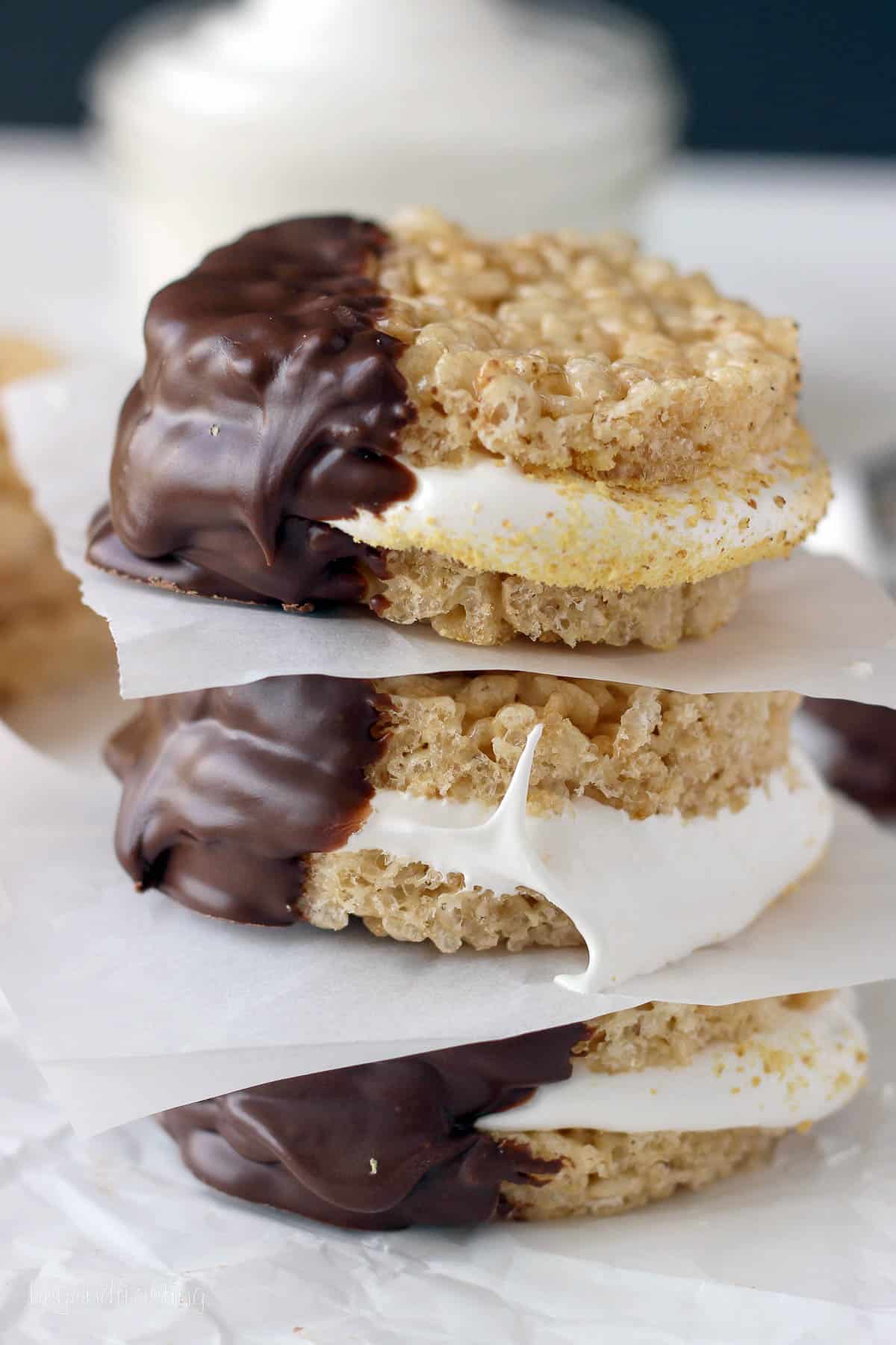 three rice krispie treat s'mores stacked with pieces of parchment paper between each