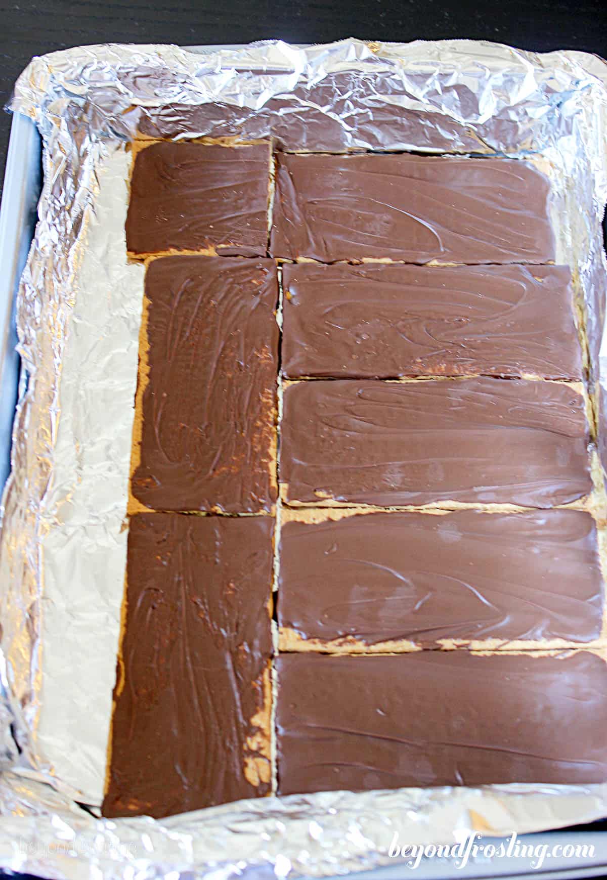 graham crackers being layered into a baking dish for ice cream sandwiches