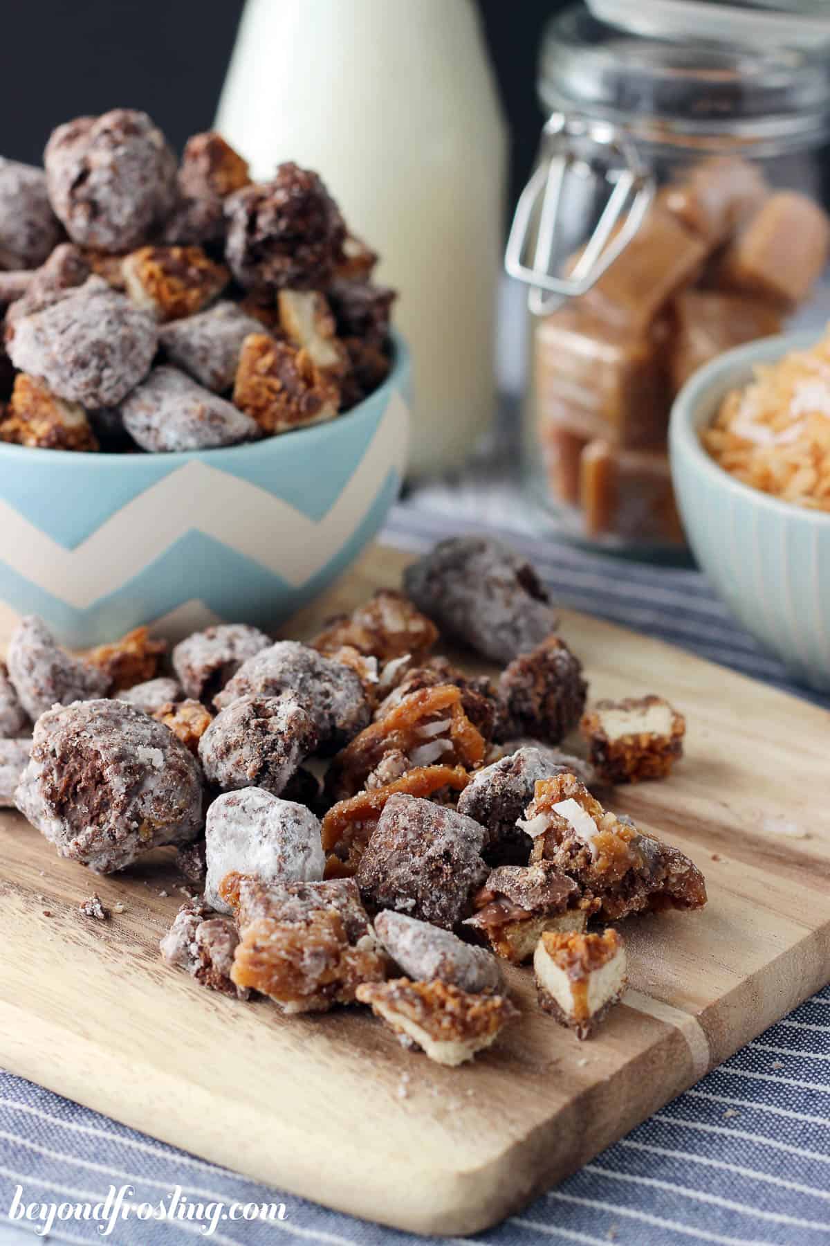 samoa muddy buddies on a cutting board with a bowl of muddy buddies in the background