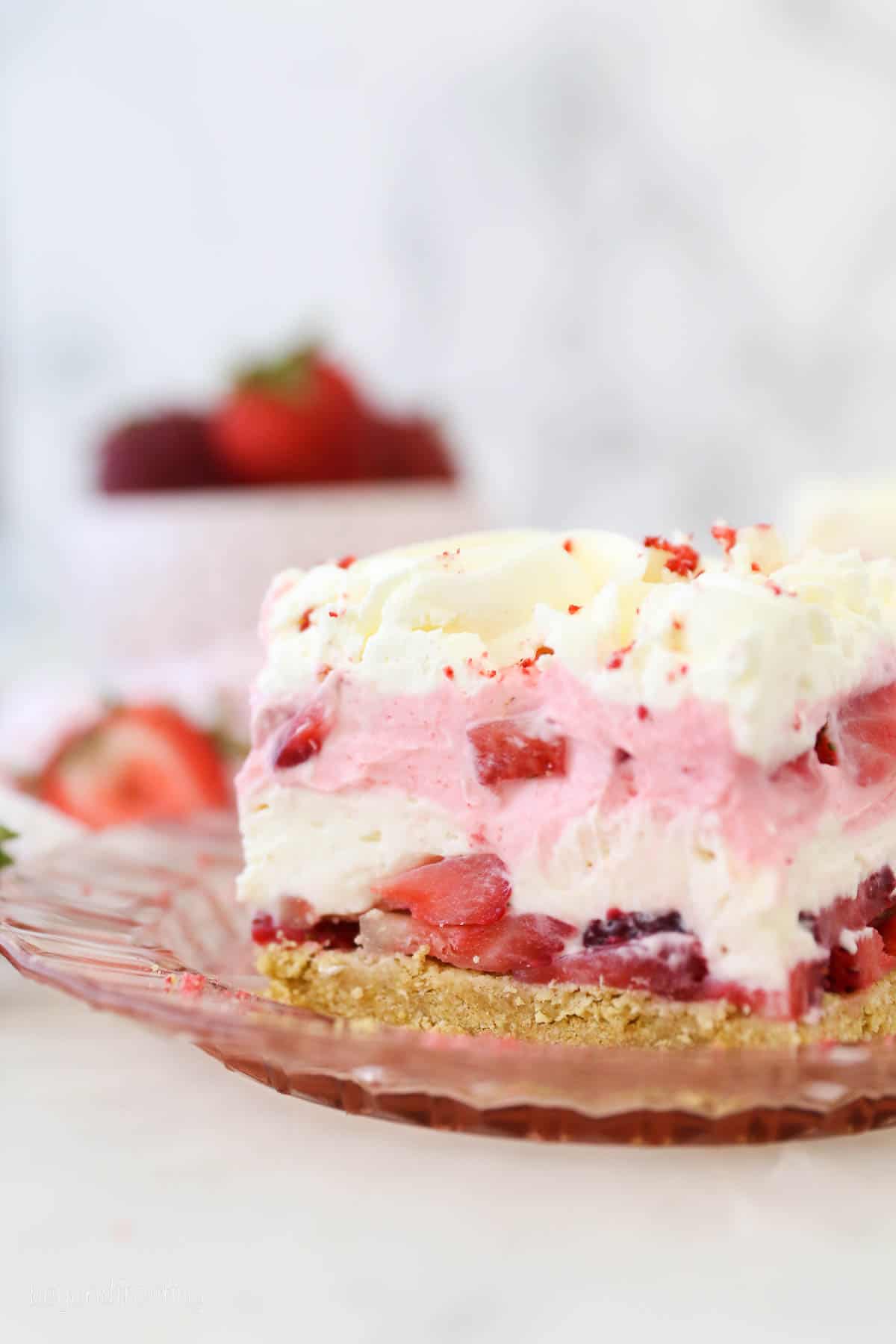 A pink glass plate with a slice of strawberry delight