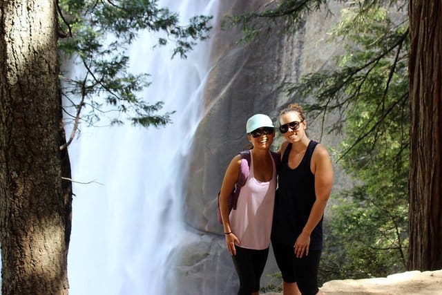 Two friends posing in front of a waterfall at Bass Lake