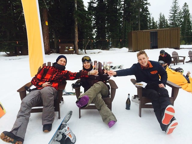 Three friends relaxing in adirondack chairs in the snow