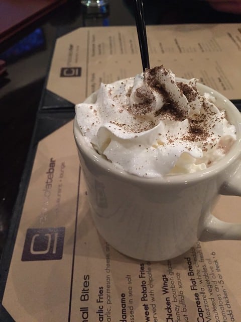 A hot drink in a mug topped with whipped cream