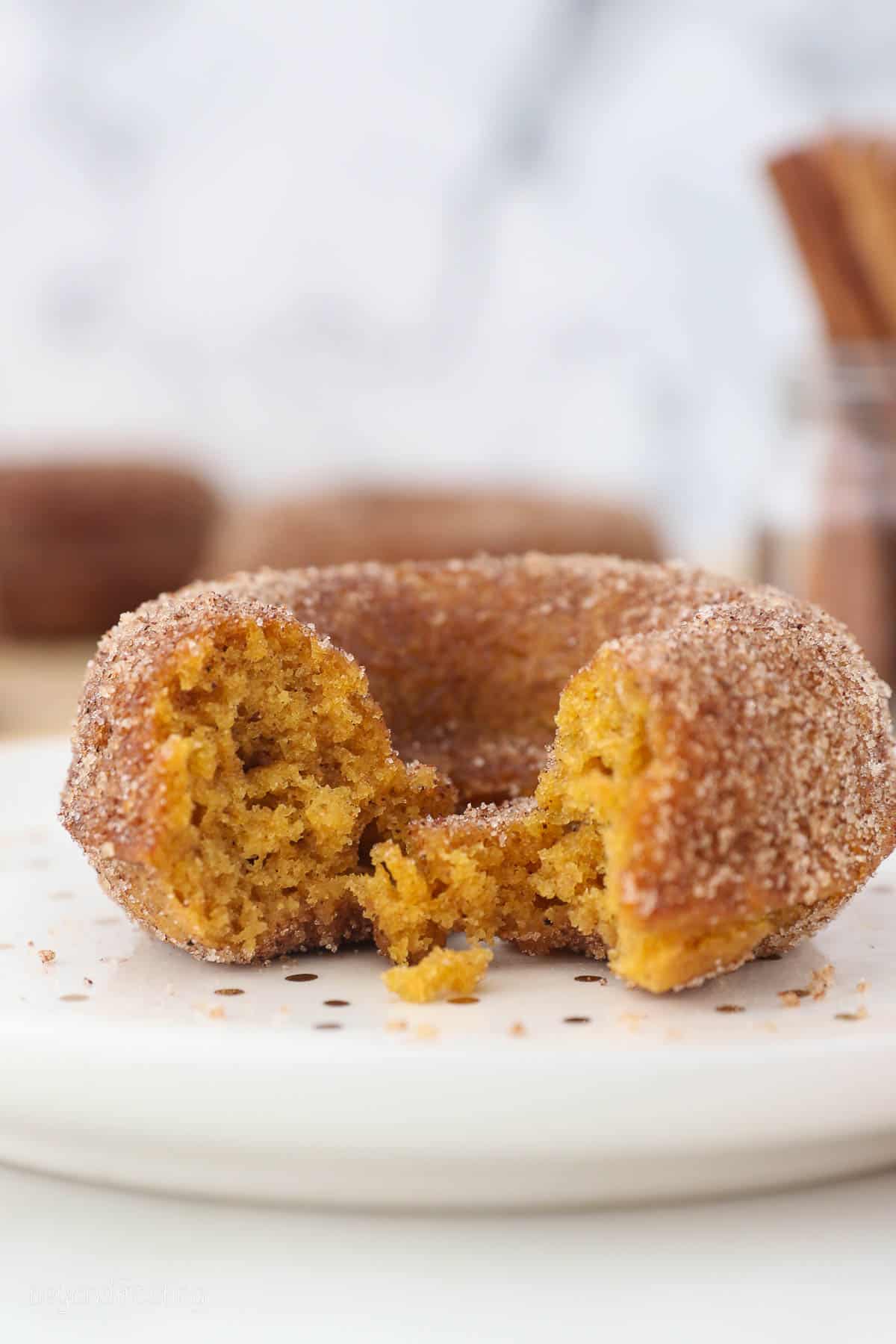 side view of a baked donut with a bite taken out on a plate