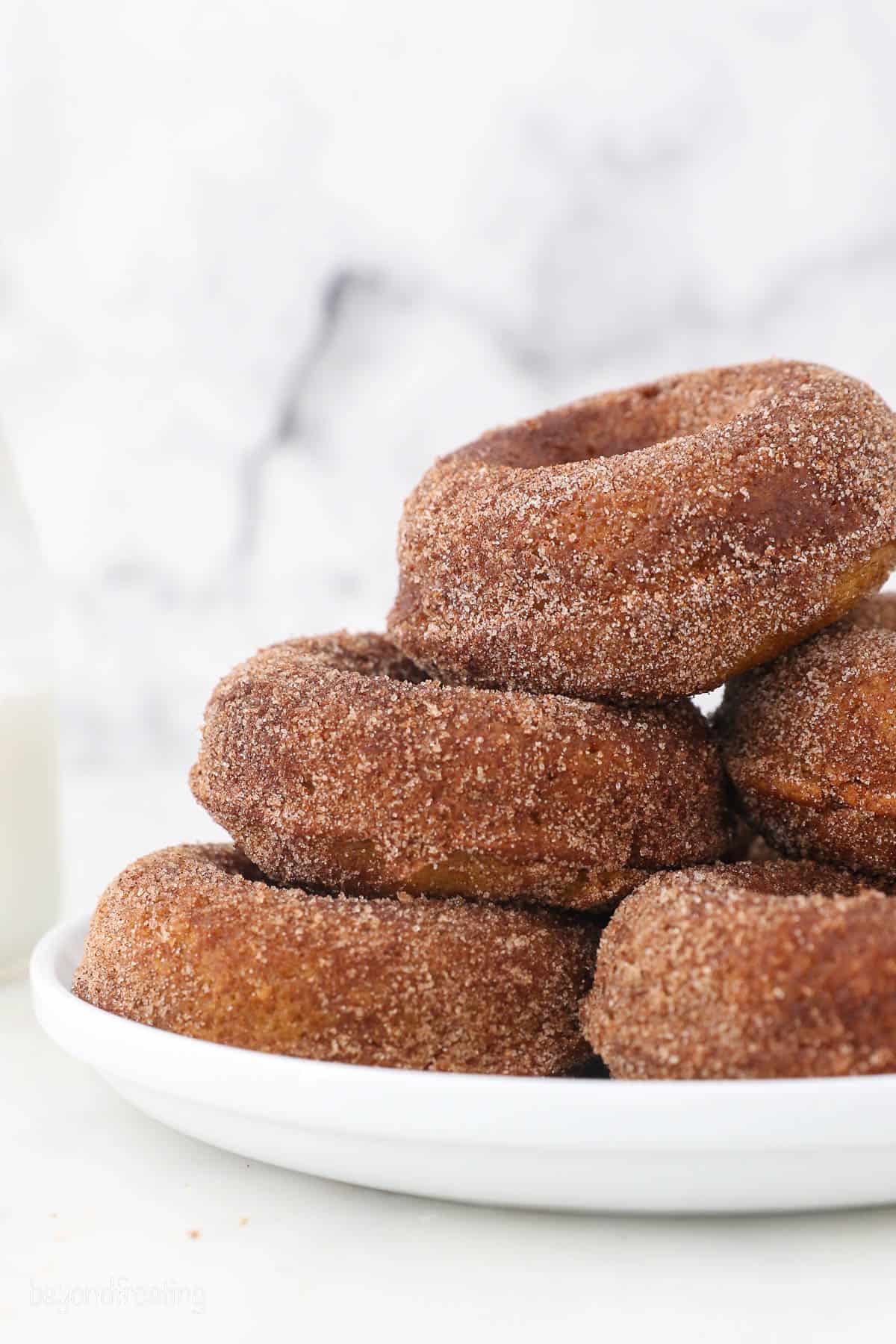 side view of a pile of pumpkin donuts on a white plate