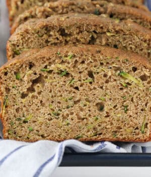 Slices of whole wheat zucchini bread on a plate with a blue striped napkin.