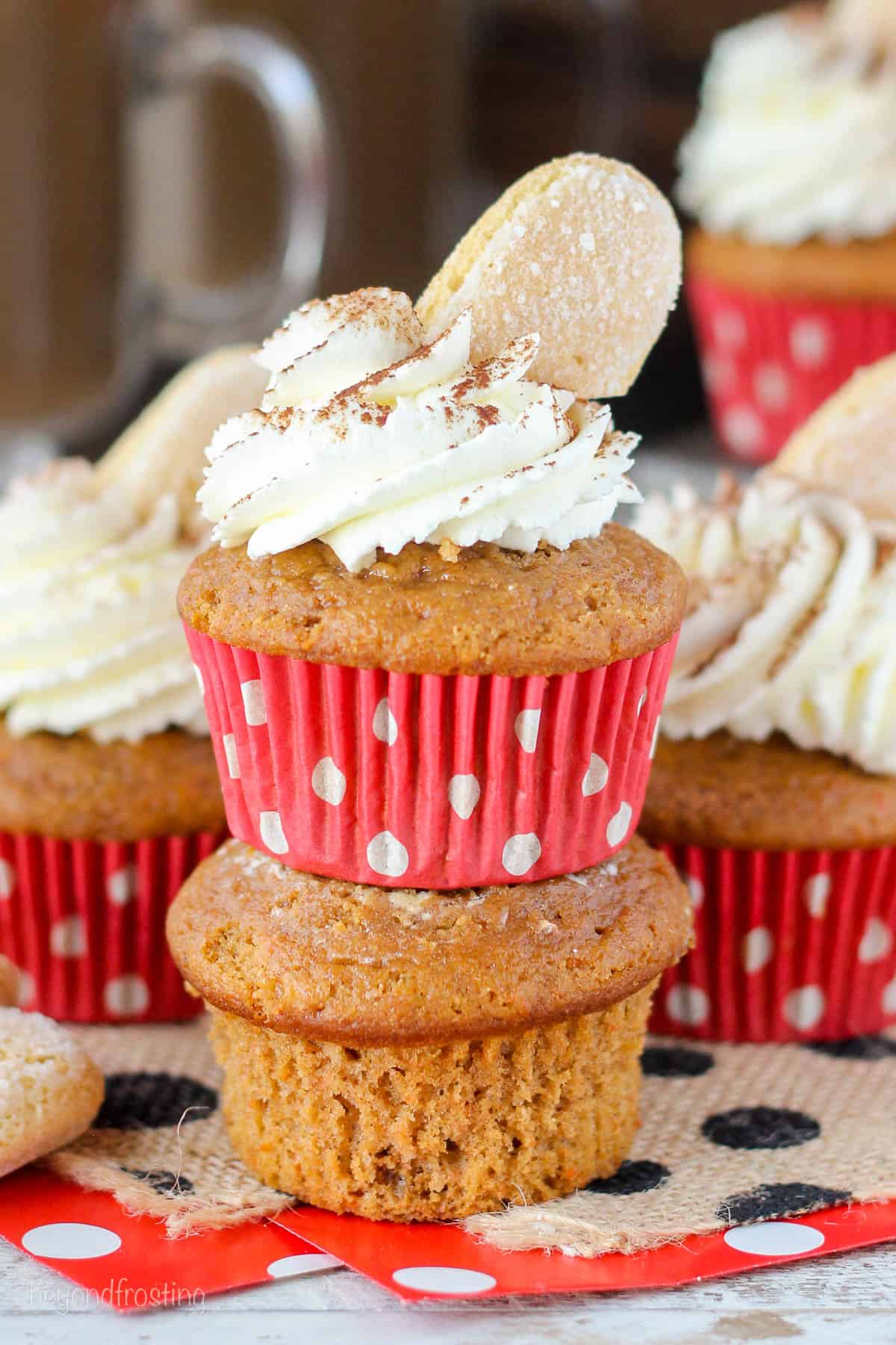 two pumpkin cupcakes stacked with whipped cream and a ladyfinger on the top one
