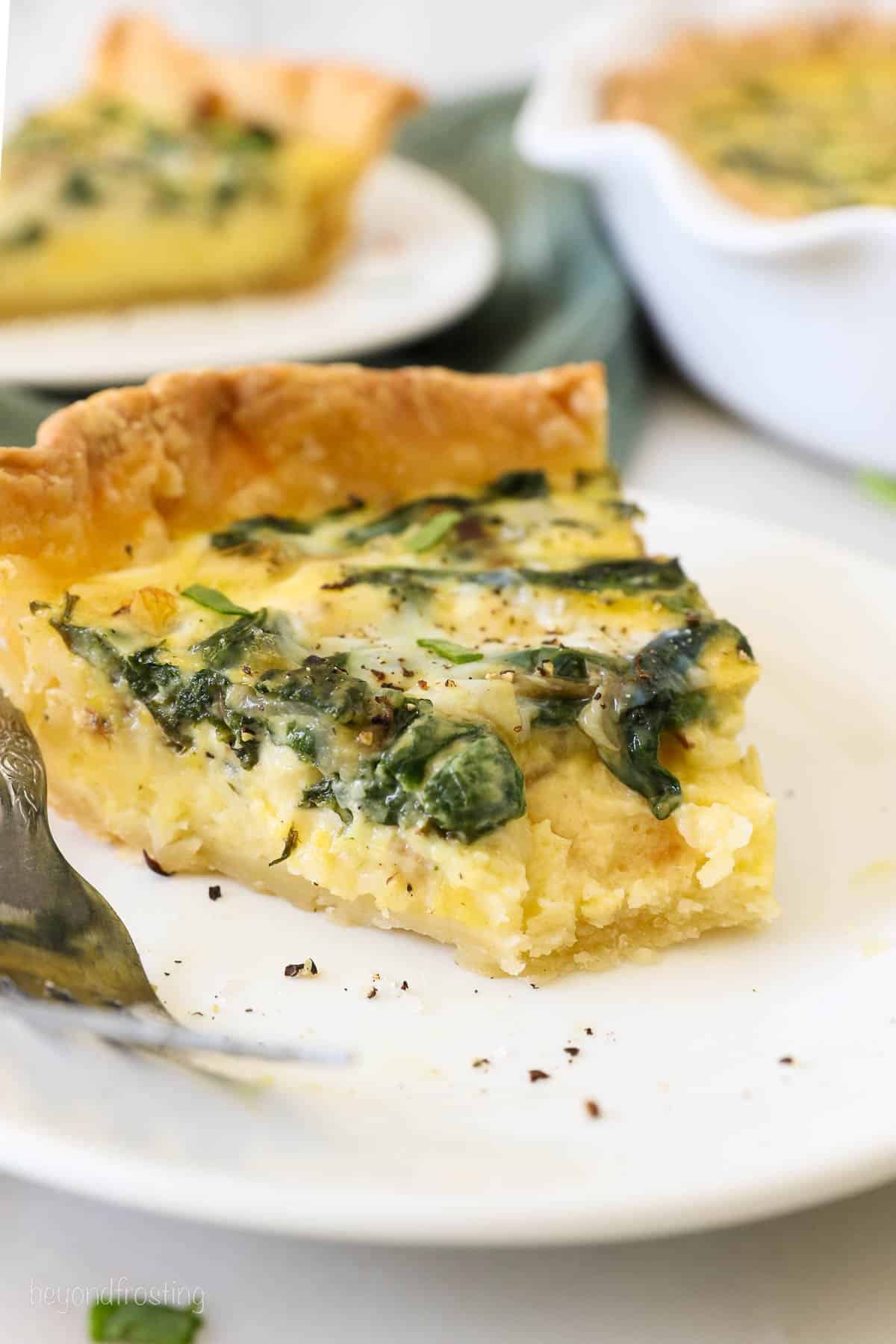 A slice of quiche florentine with a bite missing