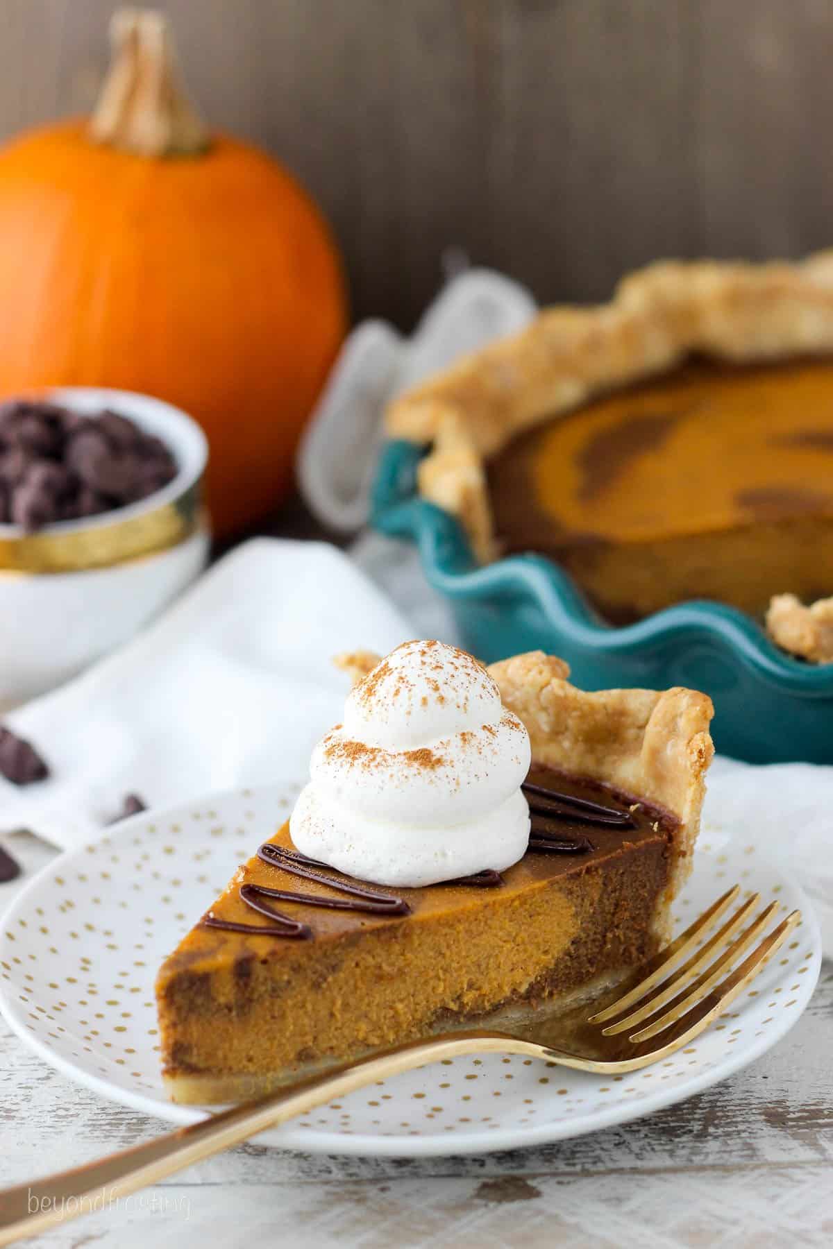 a slice of pumpkin pie on a white plate with a gold fork