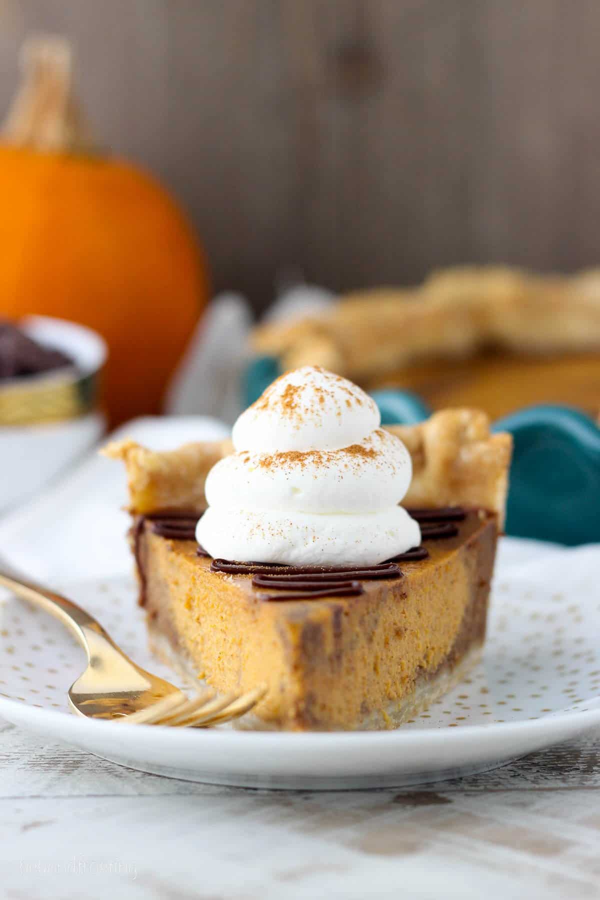 front view of a slice of chocolate pumpkin pie topped with whipped cream and chocolate ganache