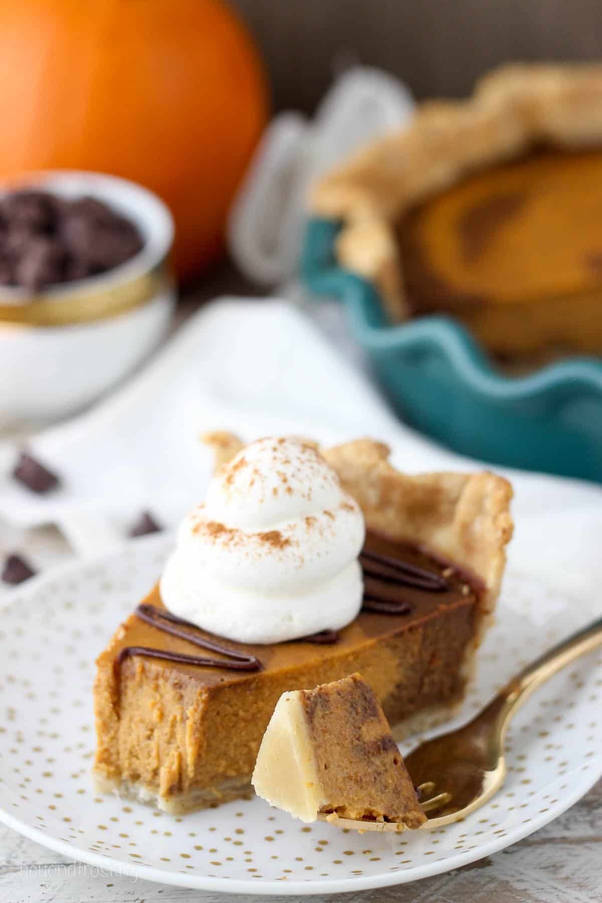a slice of pumpkin pie on a white plate with gold flecks with a bite taken out