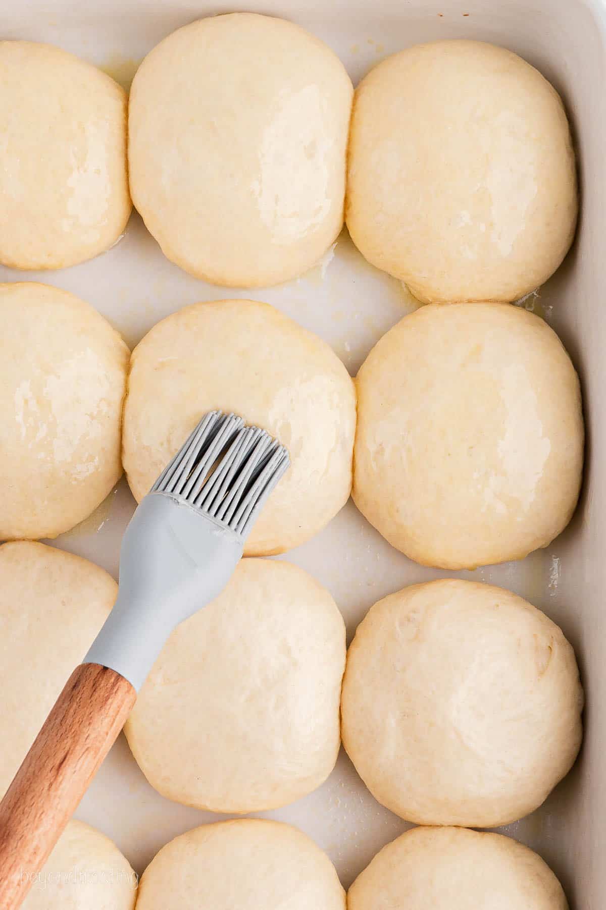 Butter being brushed on unbaked rolls