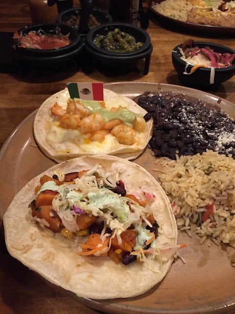 Overhead view of a plate with two tacos and a side of beans and rice