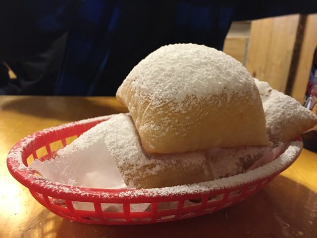Beignets in a plastic basket topped with powdered sugar