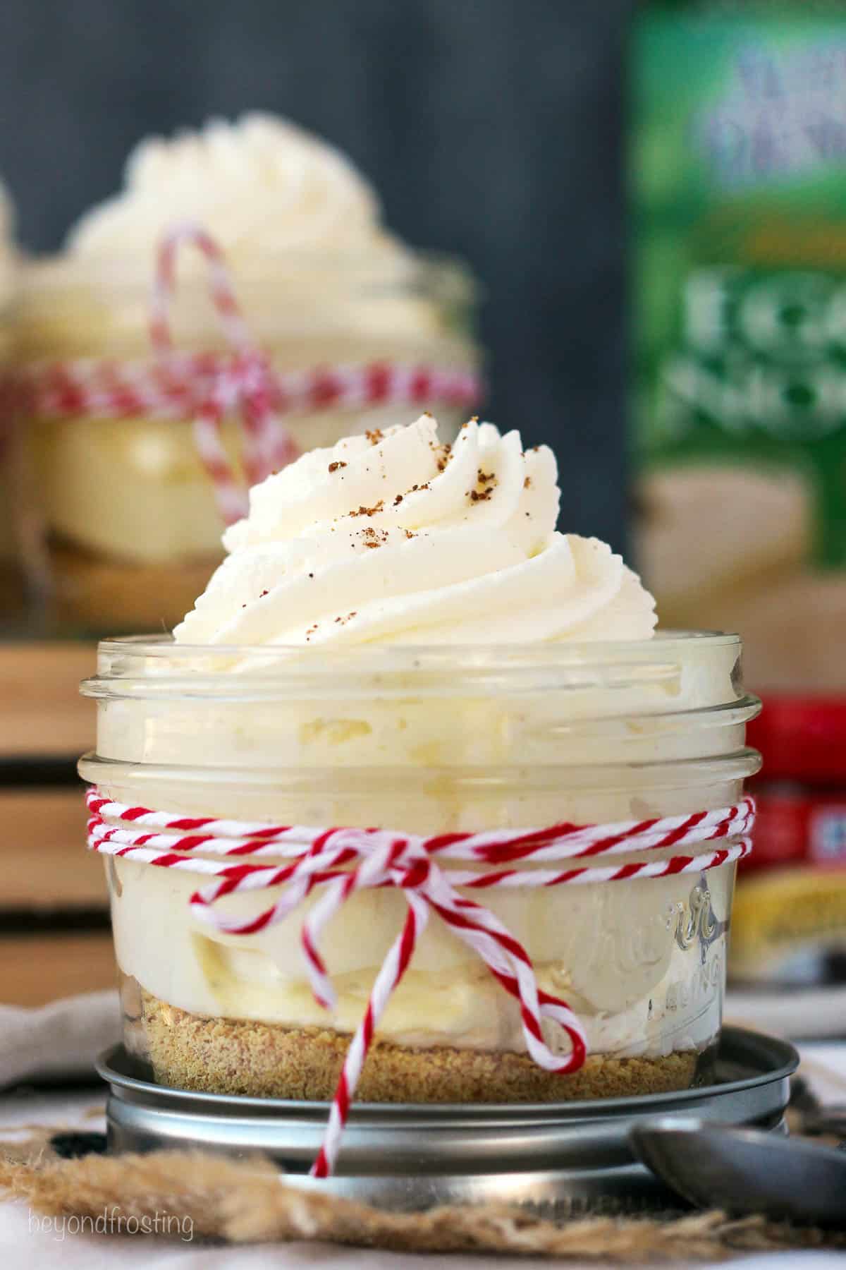 side view of a mason jar with a spiked eggnog cream pie parfait tied with a red and white piece of twine