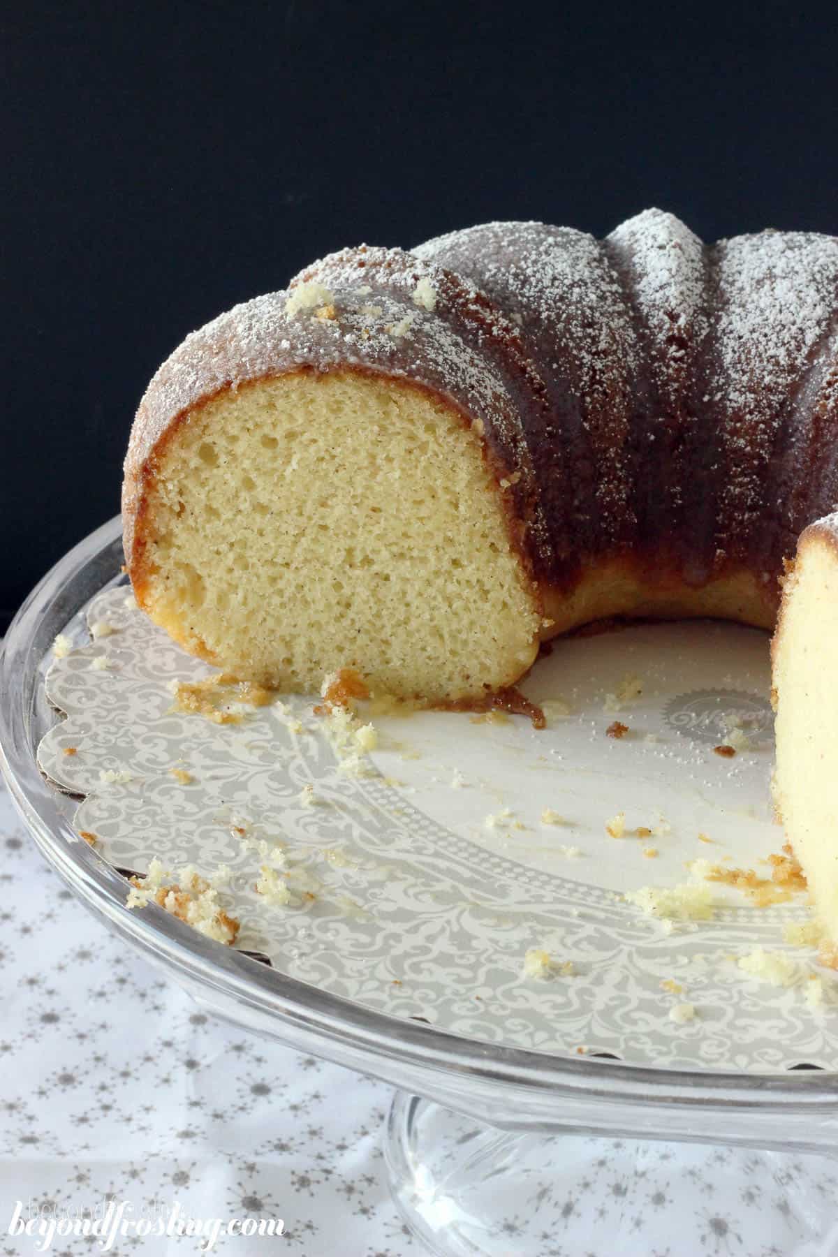 an eggnog bundt cake on a cake stand with some pieces sliced out