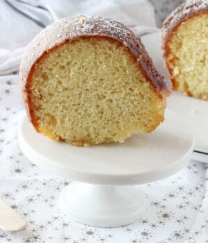 side view of a chunk of eggnog bundt cake on a white cupcake stand