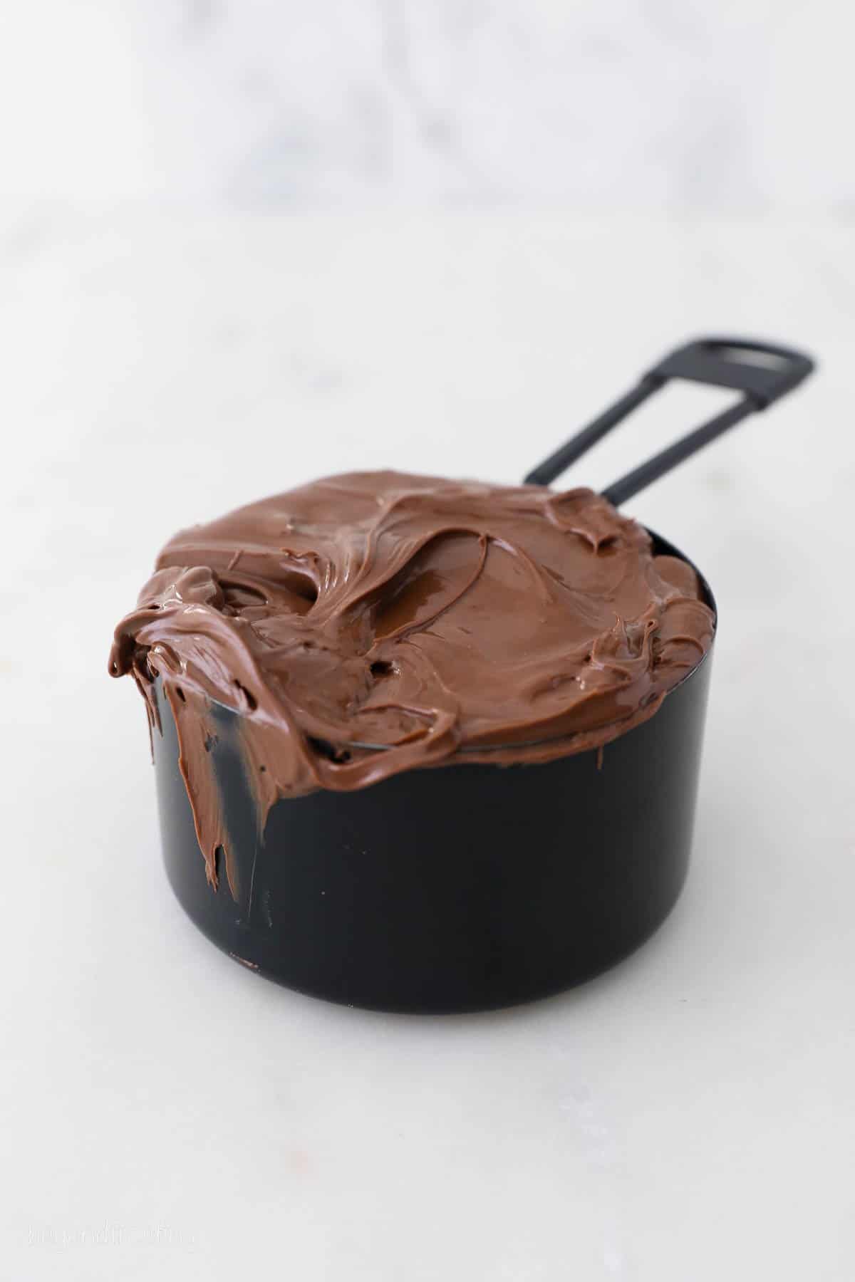 Nutella in a black measuring cup.