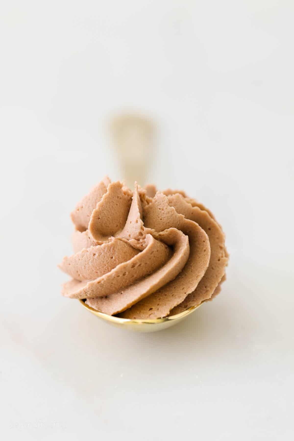 Looking down on a swirl of Nutella buttercream icing in a clear glass.
