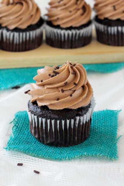 side view of a chocolate cupcake topped with peanut butter frosting and more cupcakes lined in the background