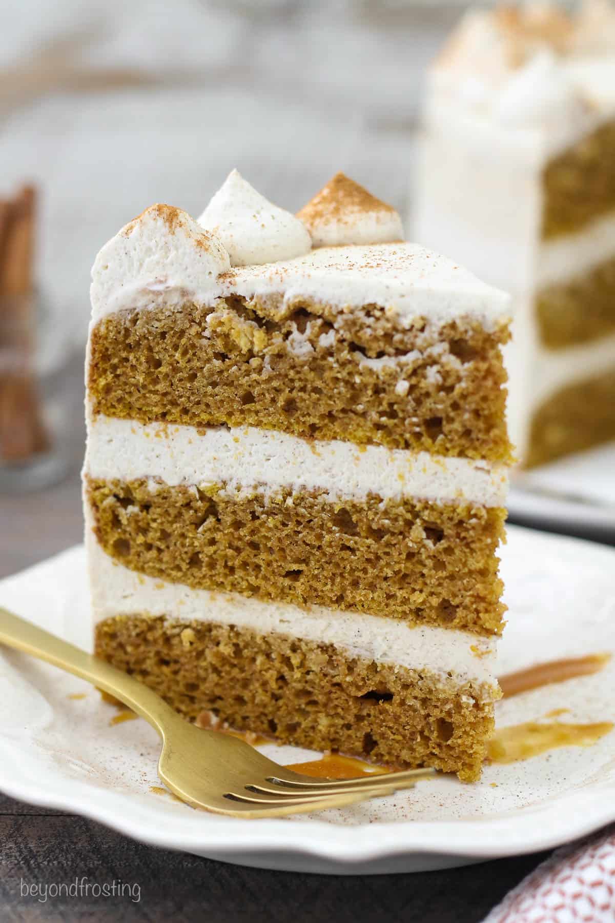 a slice of pumpkin cake standing up on a white plate next to a fork