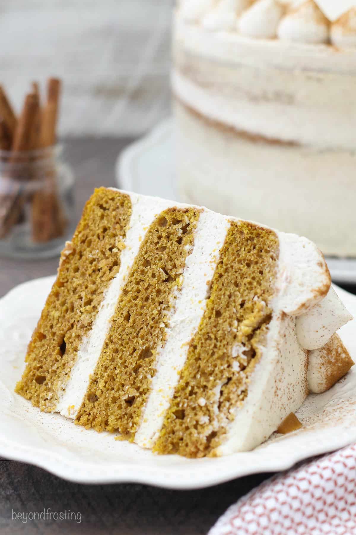 a slice of pumpkin cake with mascarpone frosting on a white plate