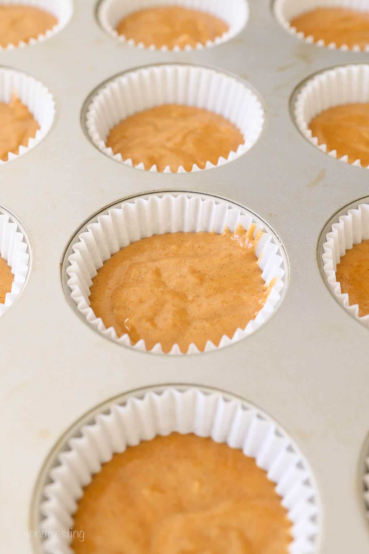 cupcake pan with liners filled with batter for pumpkin cupcakes