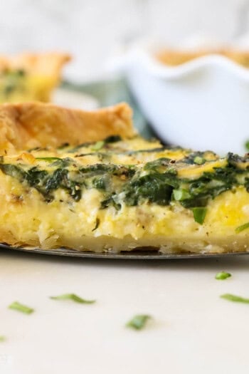 A slice of spinach and cheese quiche on a pie server