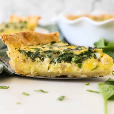A slice of spinach and cheese quiche on a pie server