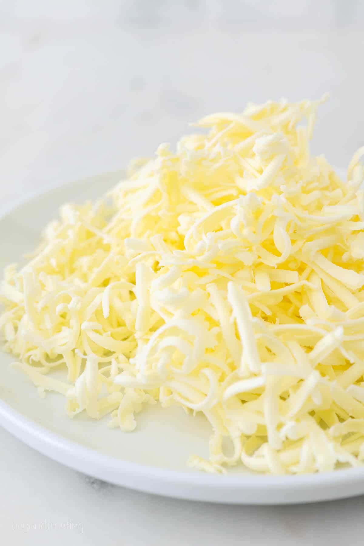 Grated cold butter for Buttermilk Biscuits is piled on a plate.