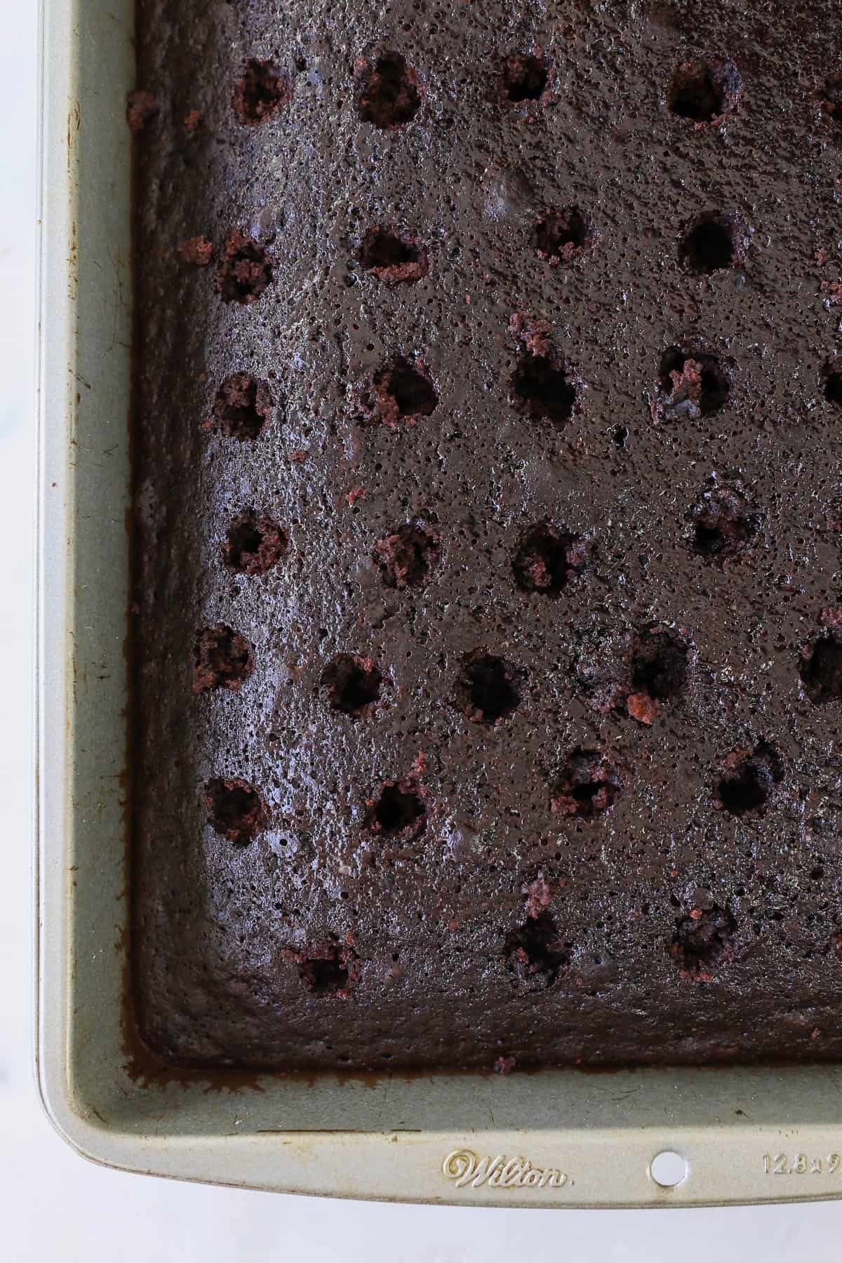 A close up of a chocolate cake with holes poked in it