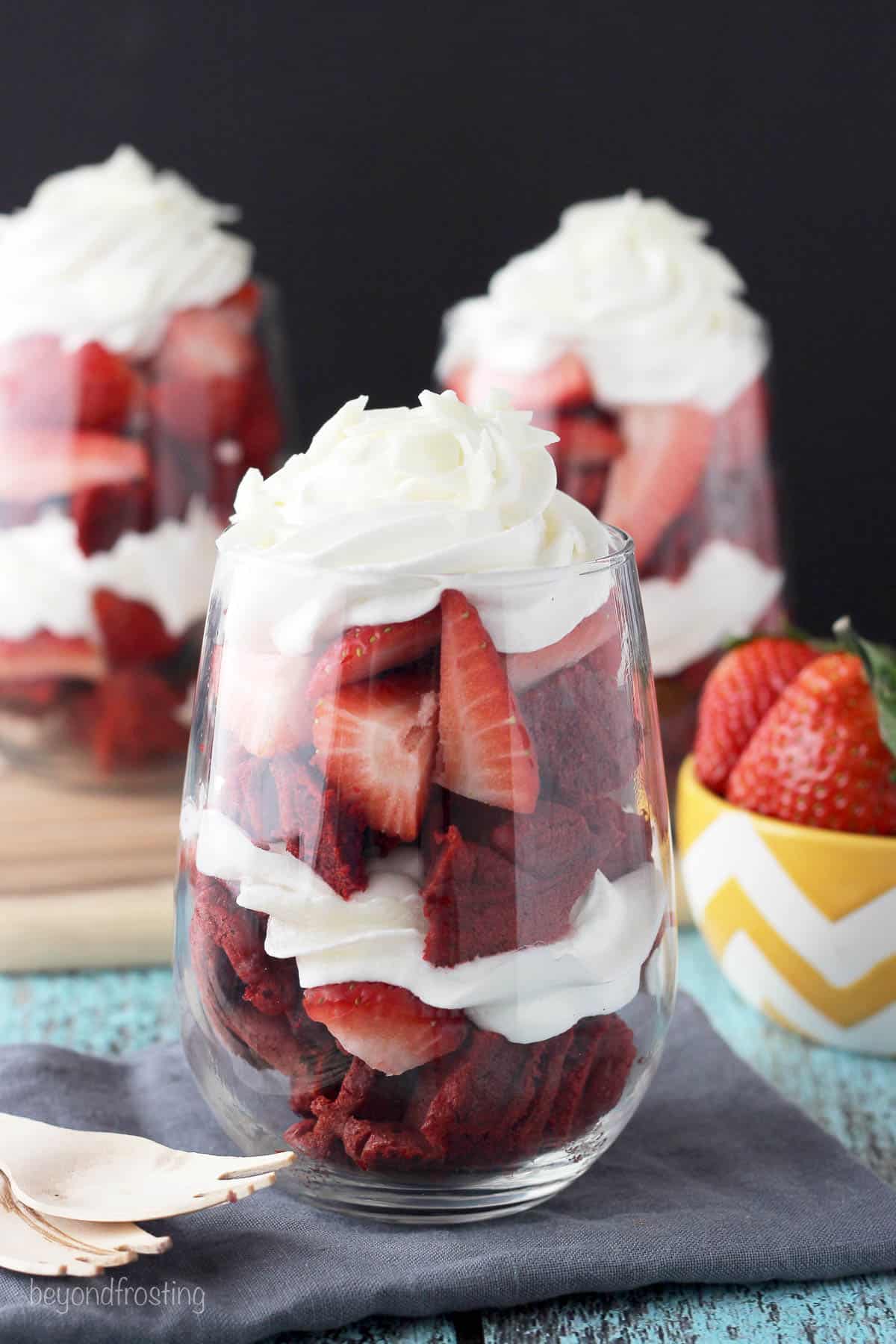 a glass filled with a strawberry red velvet waffle parfait topped with whipped cream