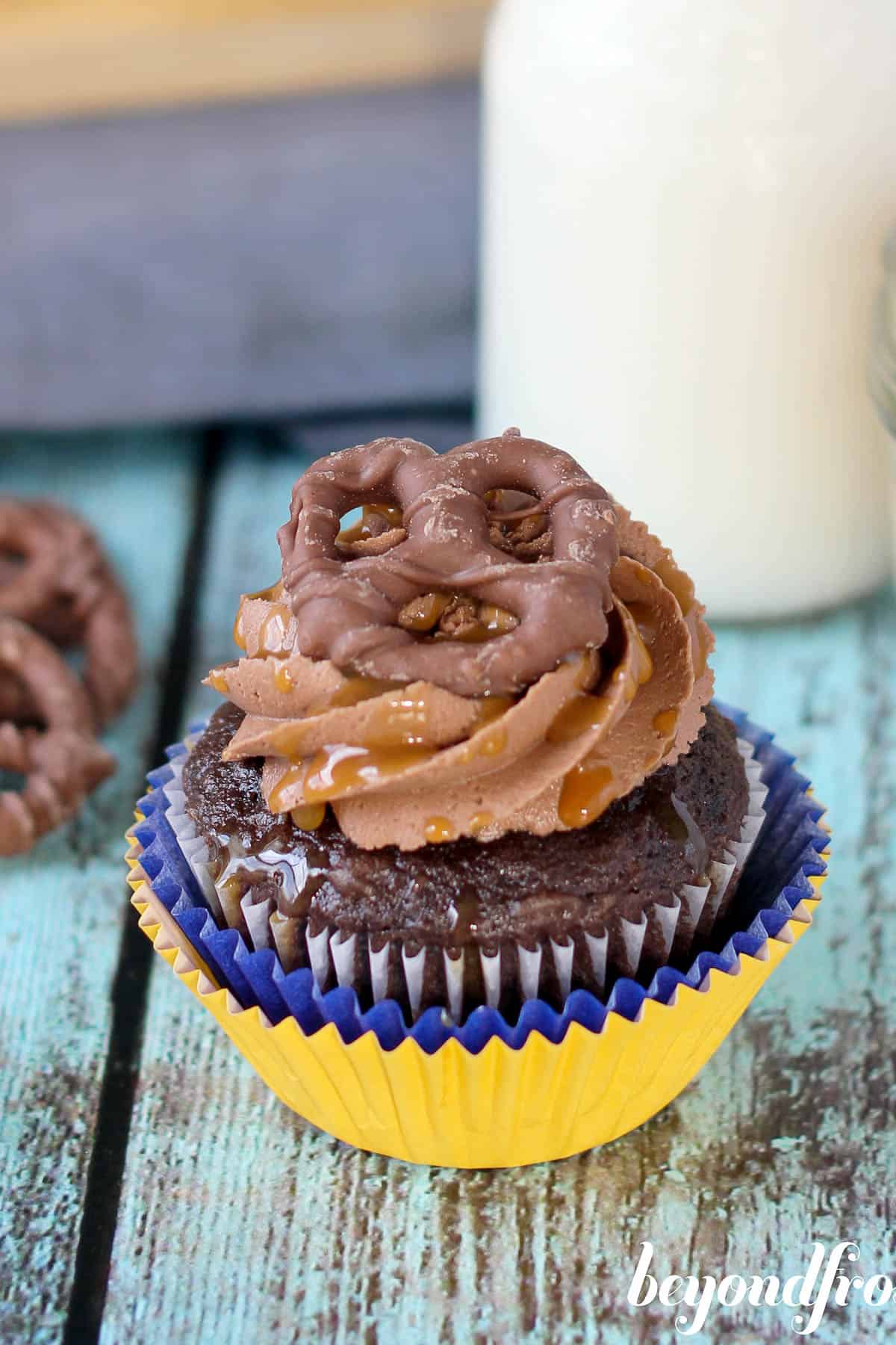 overhead of a chocolate cupcake topped with frosting and a chocolate covered pretzel