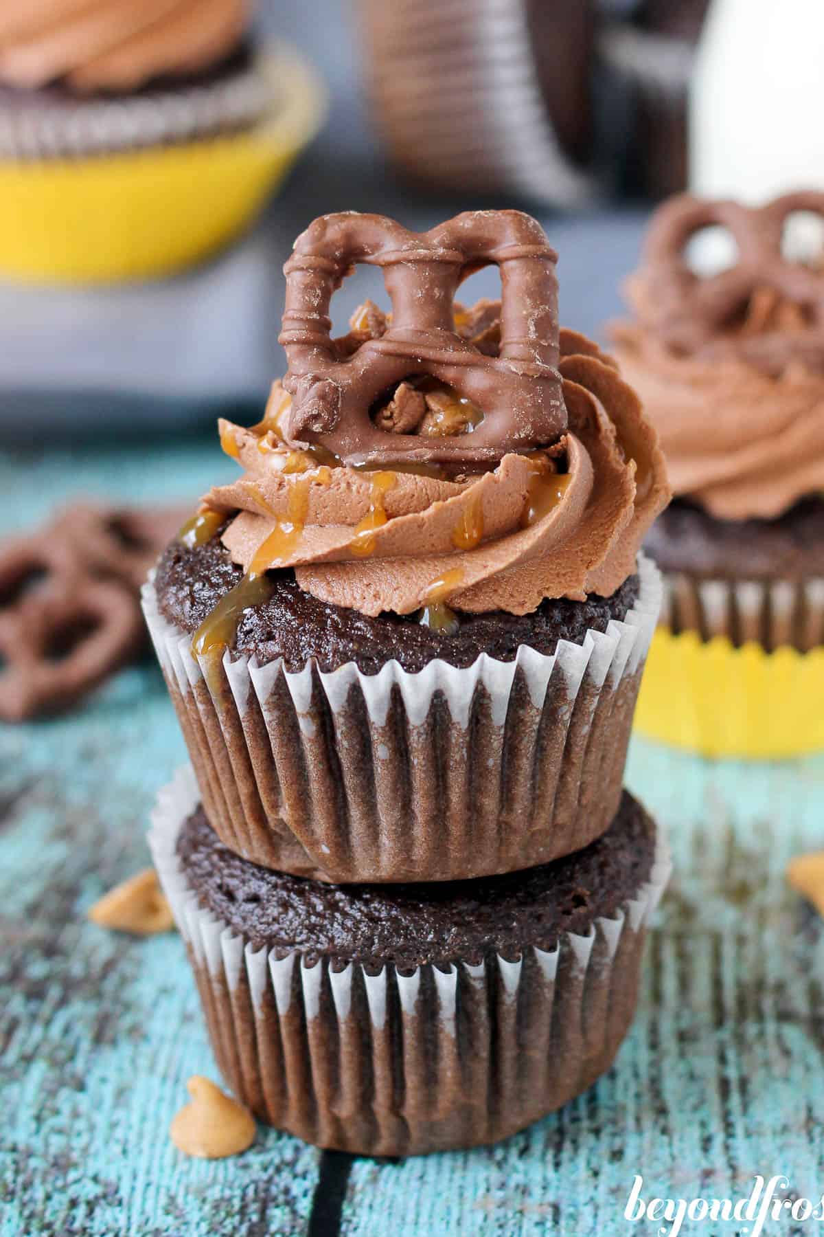 two take 5 cupcakes stacked with a chocolate covered pretzel and frosting on top