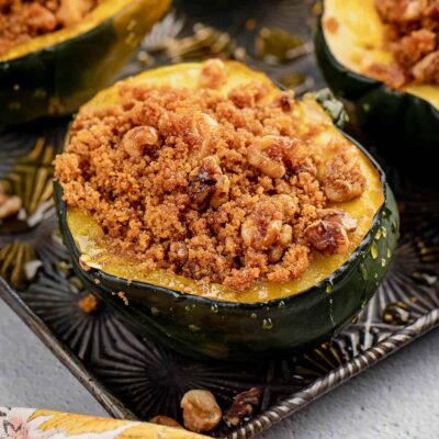 Baked acorn squash stuffed with a brown sugar and graham cracker crumble on a baking sheet.