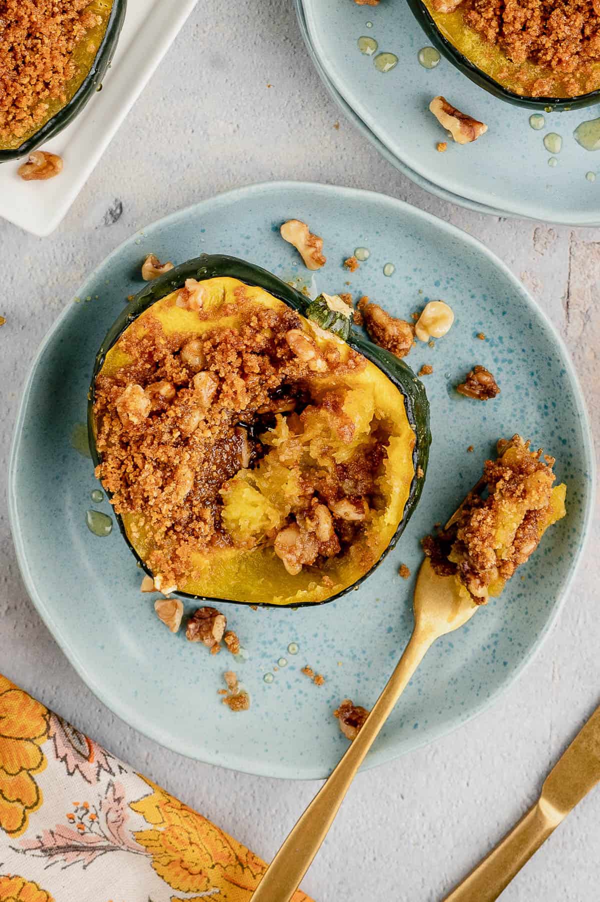 Stuffed and baked acorn squash on a blue plate next to a forkful.