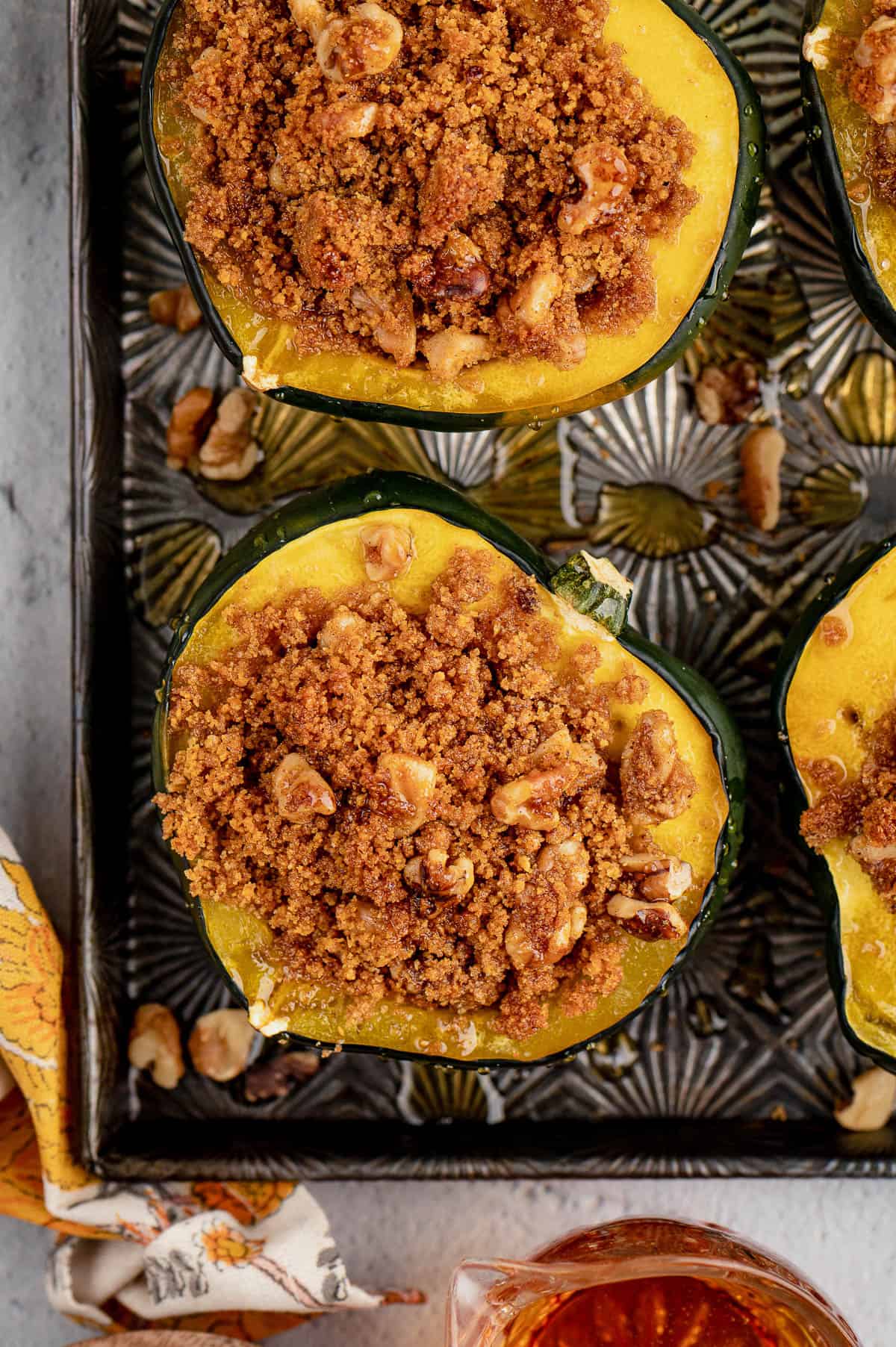 Baked acorn squash stuffed with a brown sugar and graham cracker crumble on a baking sheet.