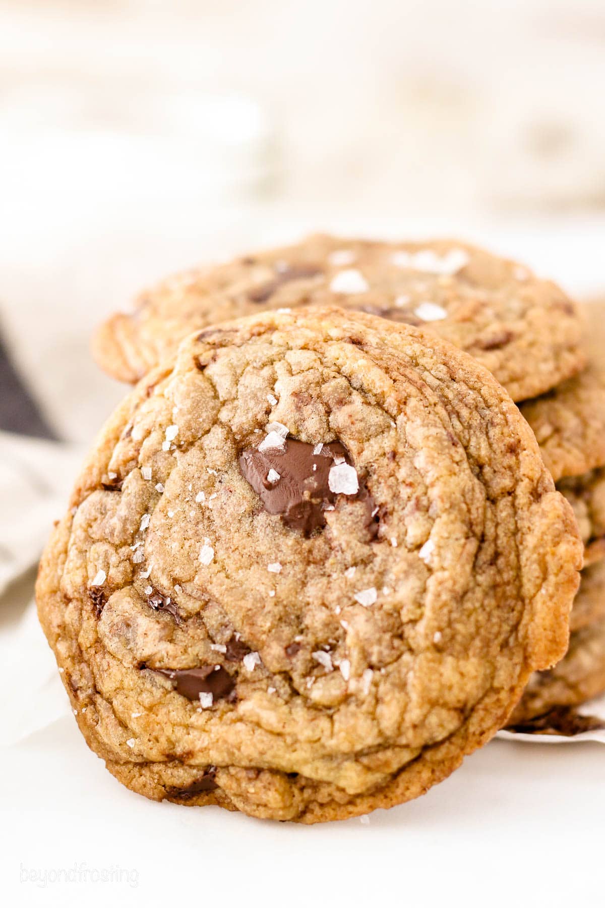 a chocolate chip cookie leaning on a stack of more cookies