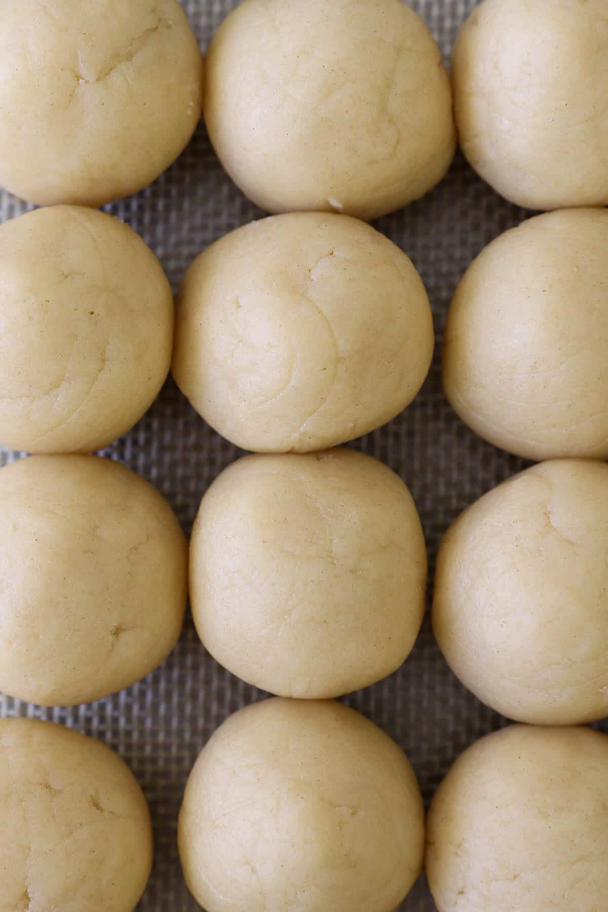 Rows of portioned cookie dough balls on a baking mat.