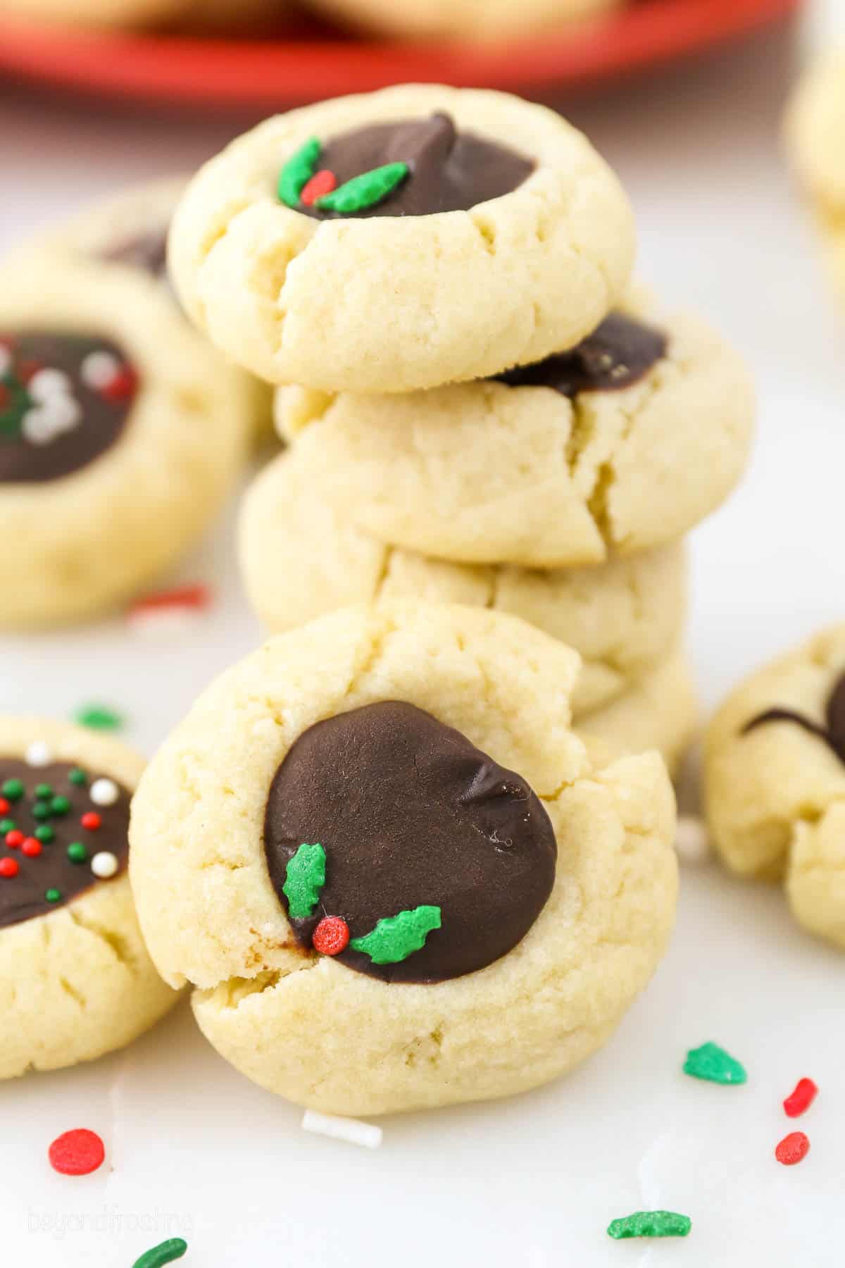 A stack of chocolate thumbprint cookies decorated with red and green sprinkles.