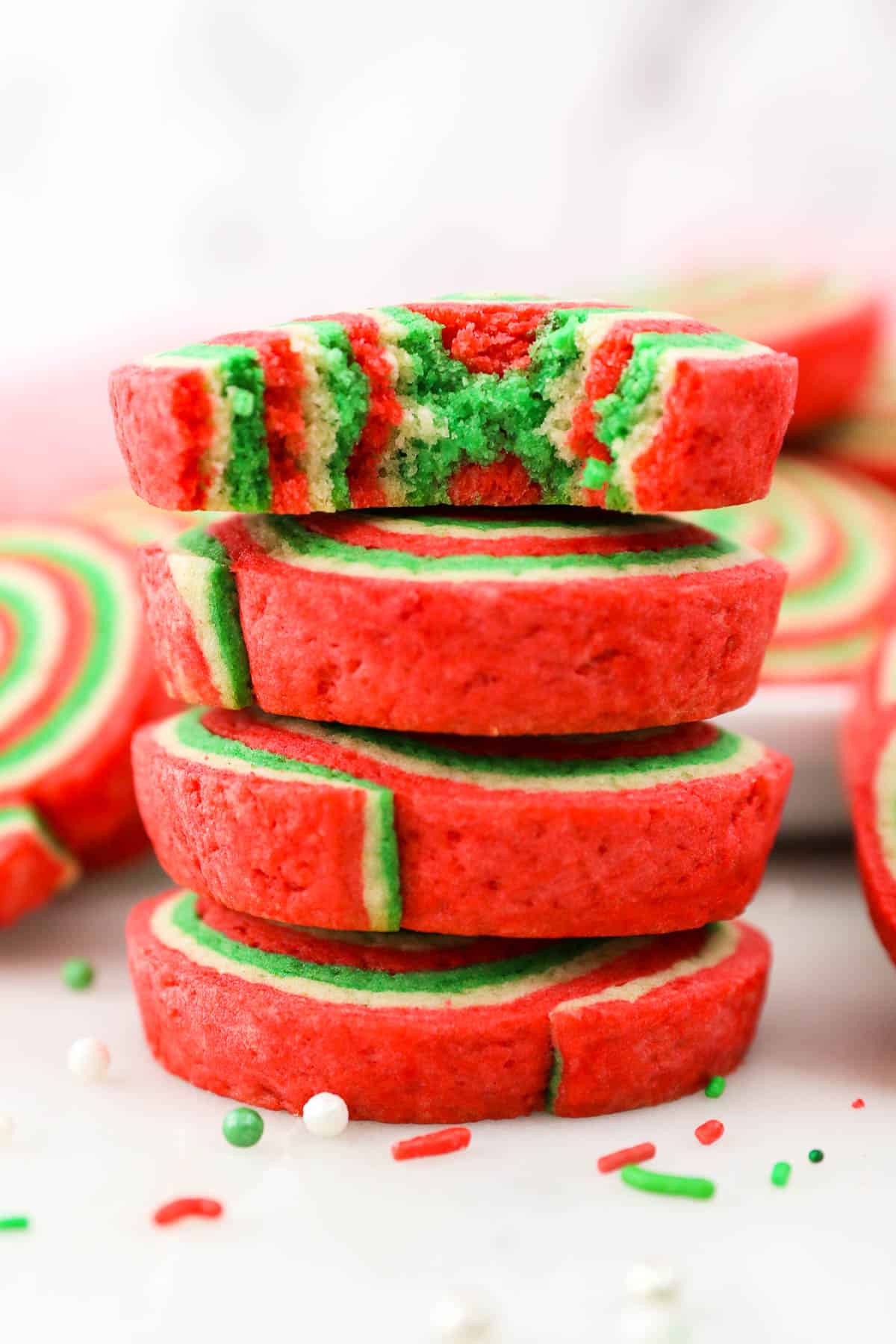 A stack of Christmas pinwheel cookies with a bite missing from the top cookie.