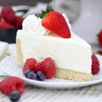 closeup side view of a slice of cheesecake on a white plate with gold flecks