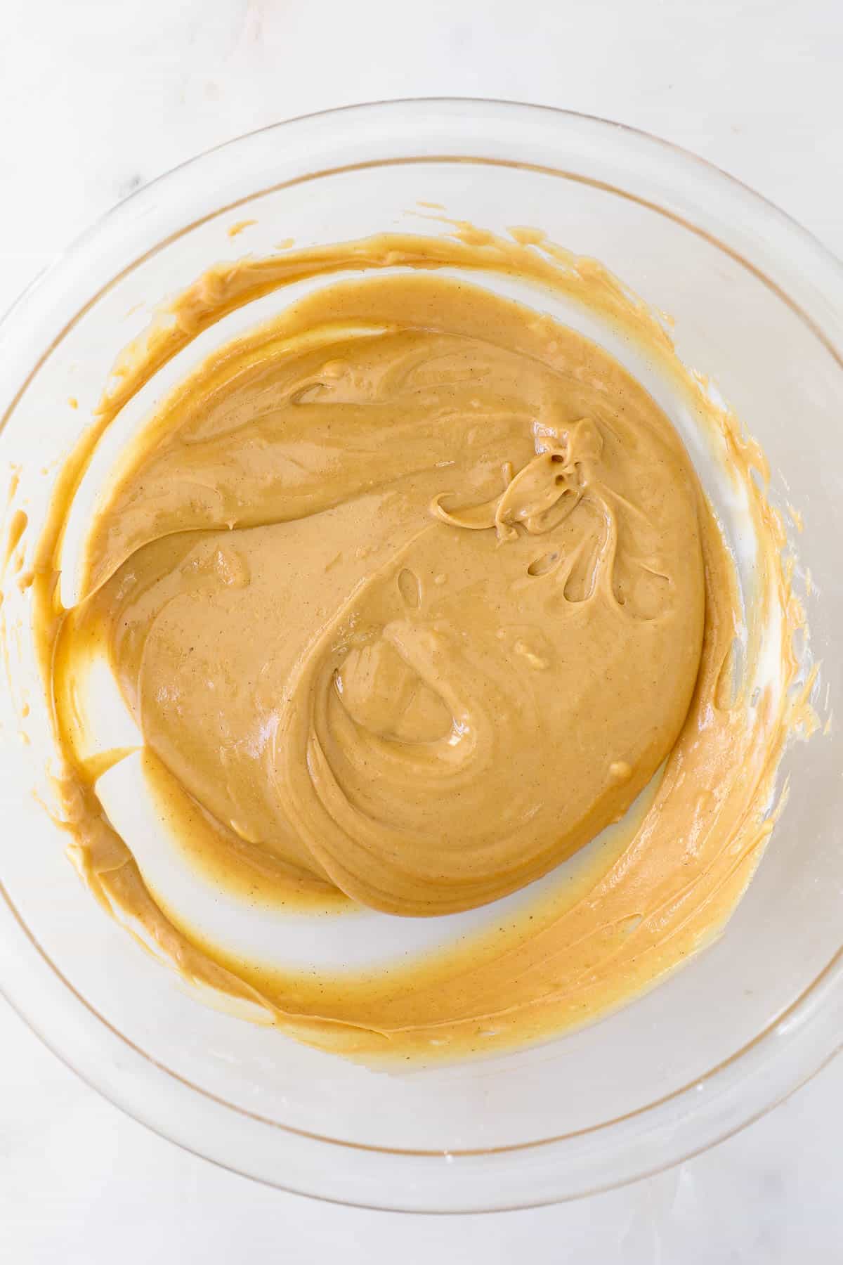 Peanut butter combined with melted butter in a mixing bowl.