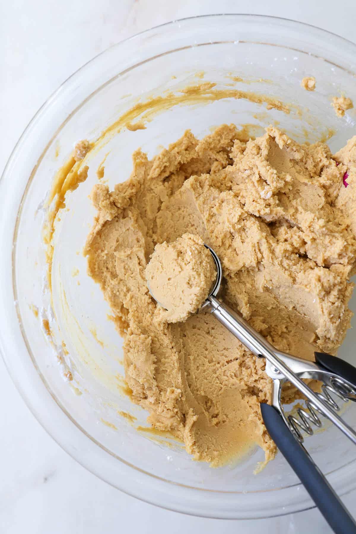 A cookie scoop in a bowl with peanut butter fudge.