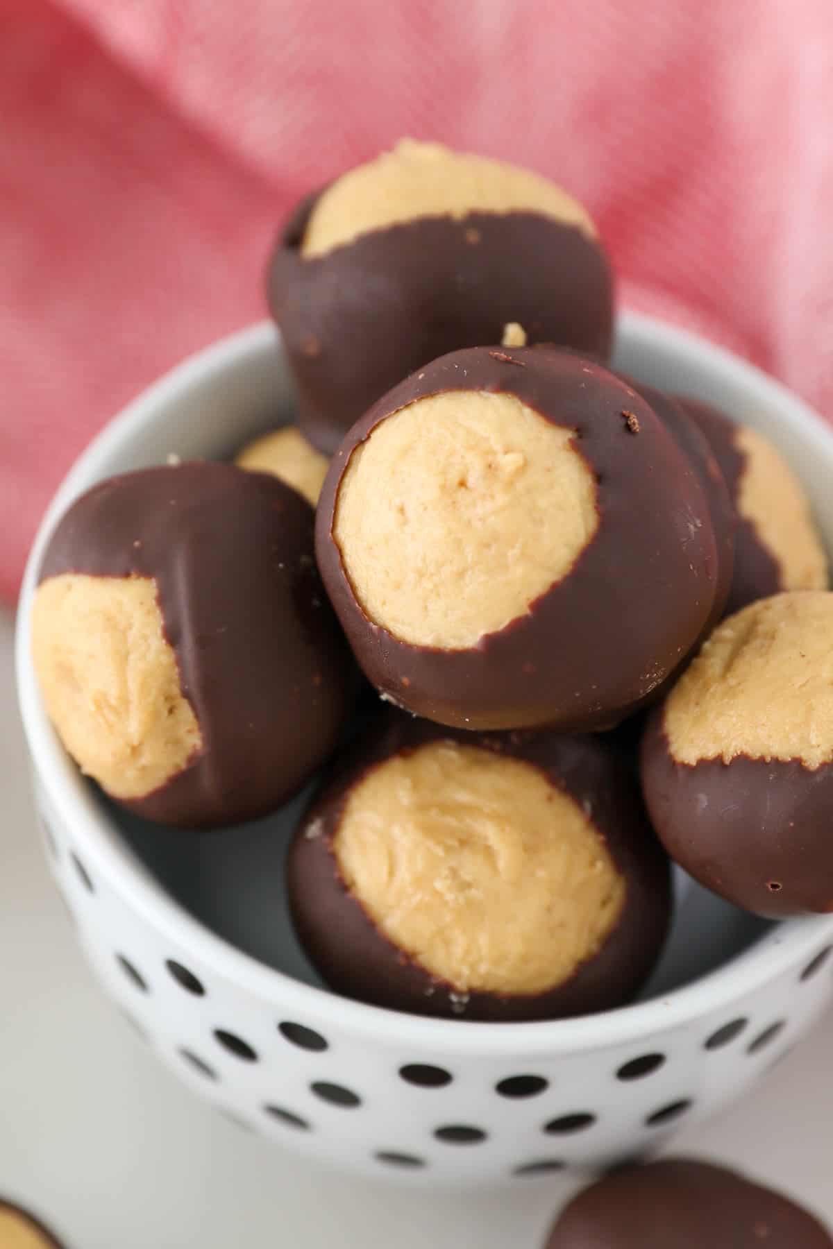 Peanut butter buckeyes in a small white bowl with black polkadots.