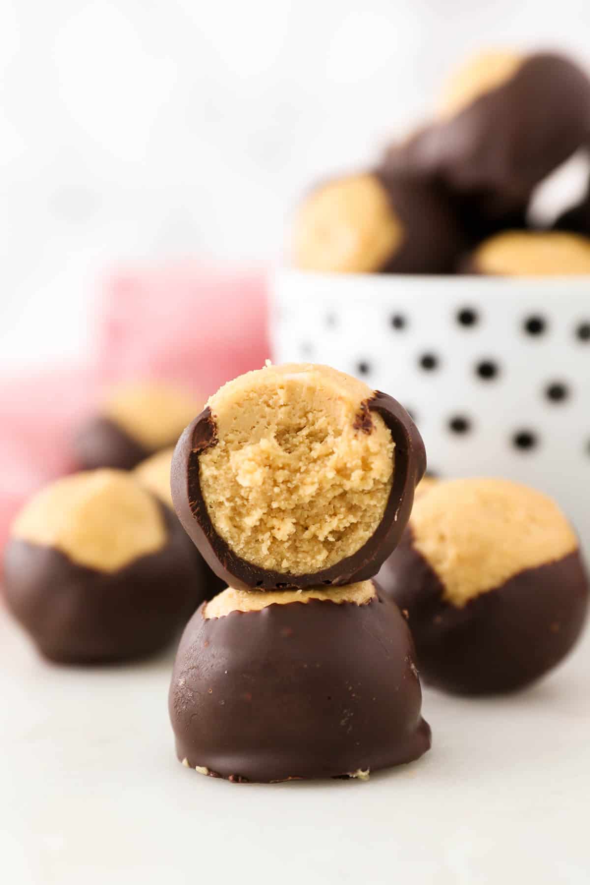 Two peanut butter buckeyes stacked on top of one another, with a bite missing from the top one.